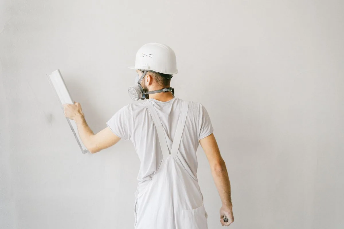 Plasterer applying plaster to wall with trowel